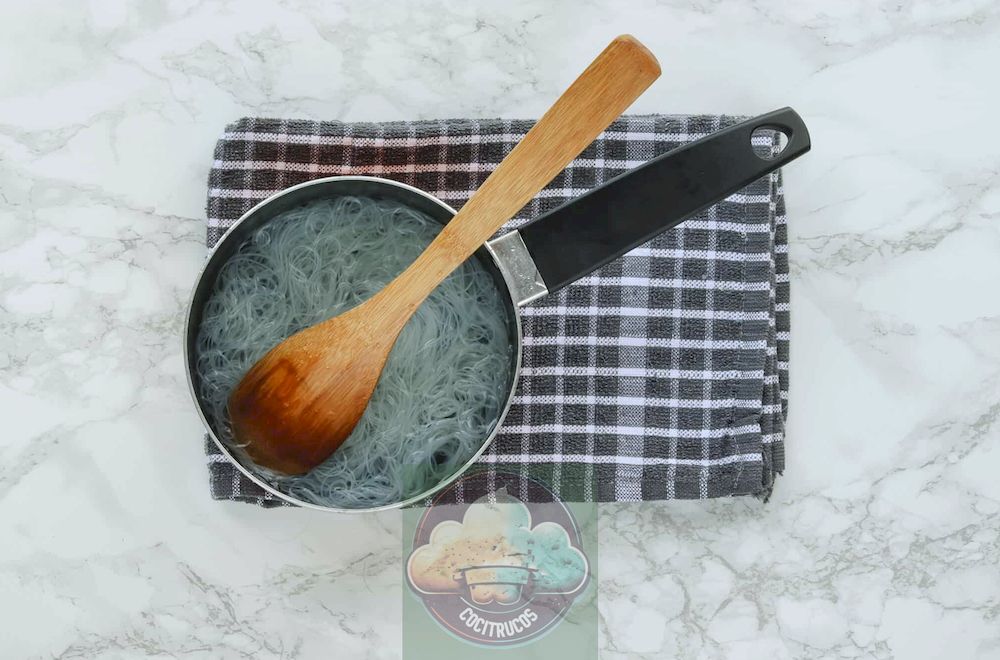 Fideos de arroz que se lavan con agua fría en una cacerola