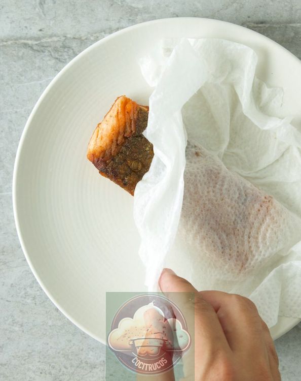 salmón cubierto con una toalla de papel húmeda en un plato apto para microondas