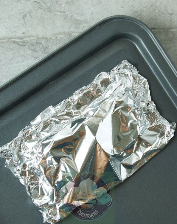 salmón en un paquete de aluminio con rodajas de limón y caldo